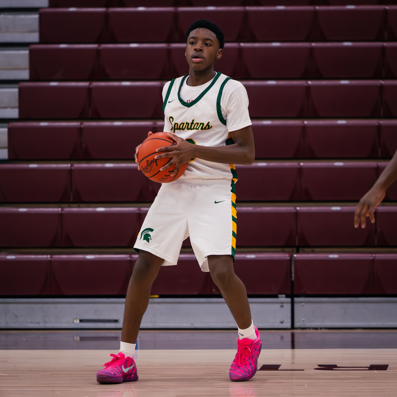 Malachi Winston on the court holding a basketball in his Start High School uniform